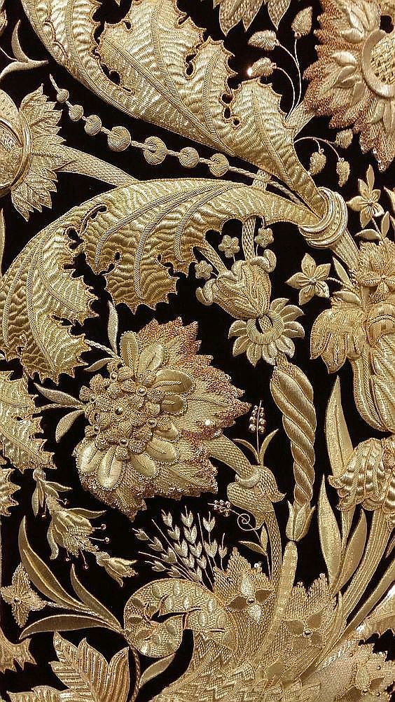 an intricately designed wallpaper with gold flowers and leaves on black velvet, closeup