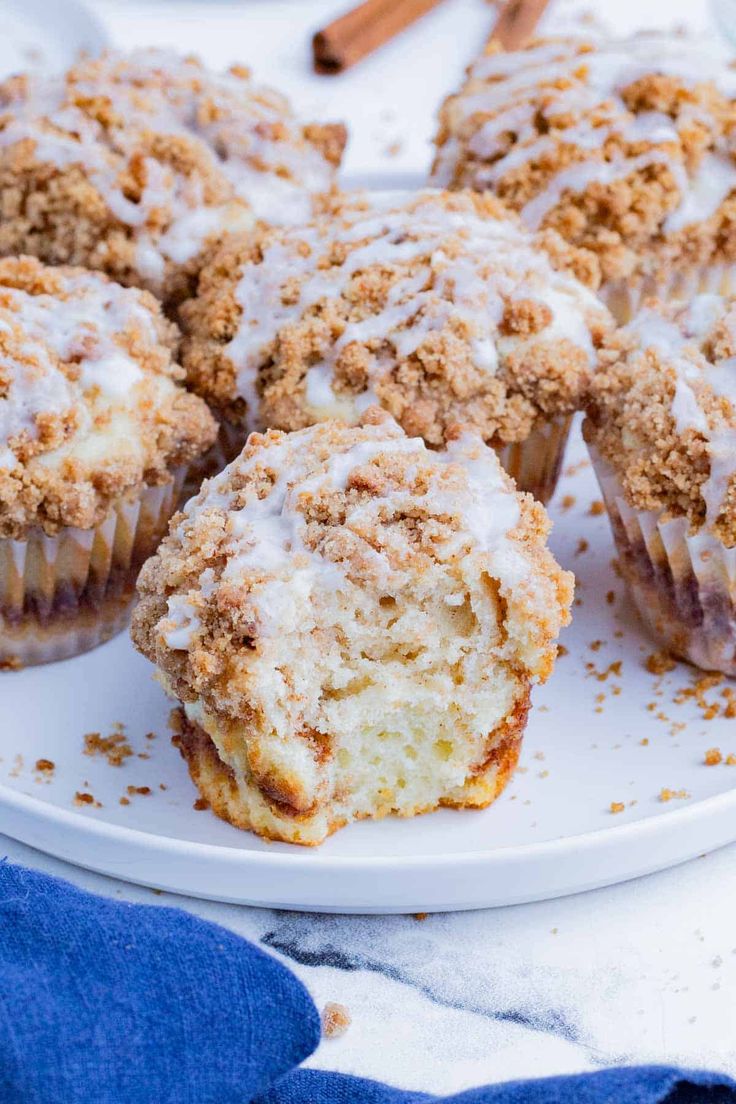 a muffin on a white plate with cinnamon sticks