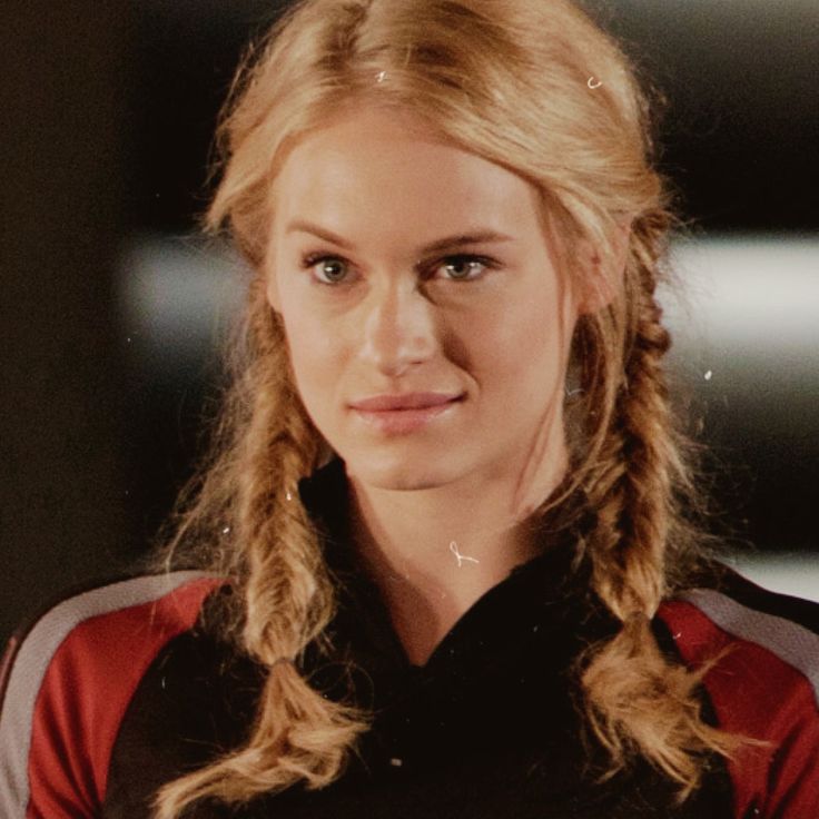 a woman with long blonde hair wearing a black and red shirt looking at the camera