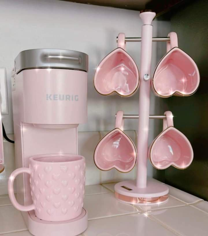 pink cups and spoons are sitting on the counter next to a coffee cup holder