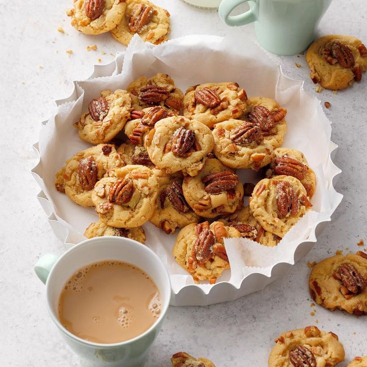 a plate full of pecan cookies next to a cup of coffee