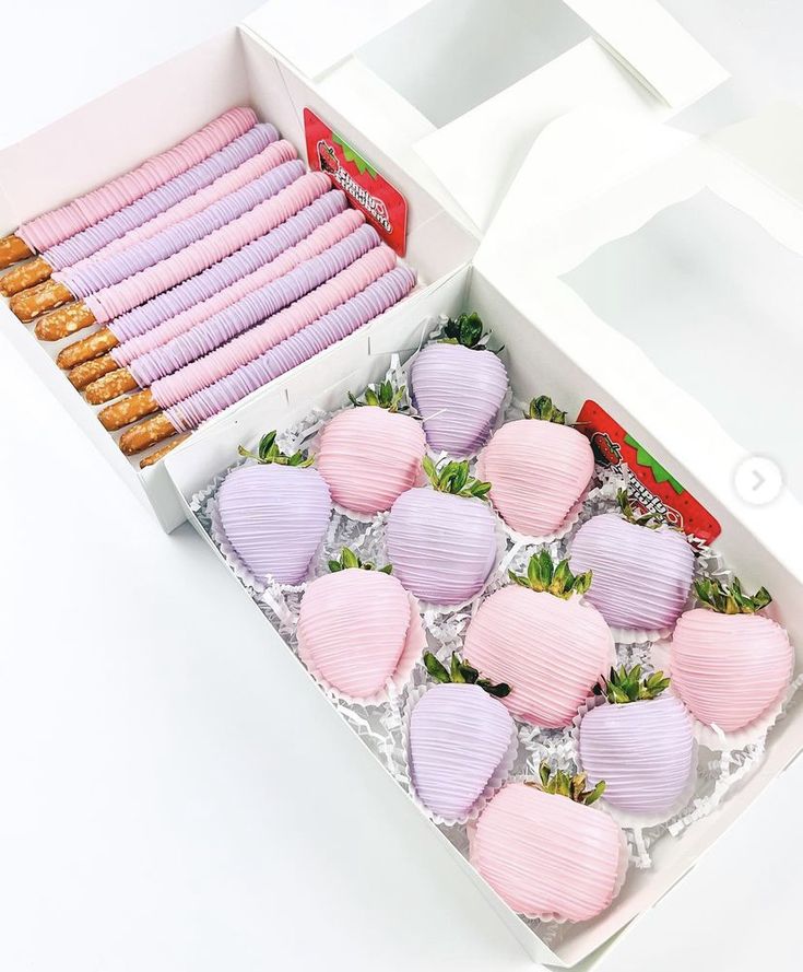 a box filled with lots of pink strawberries next to cookies in the shape of hearts