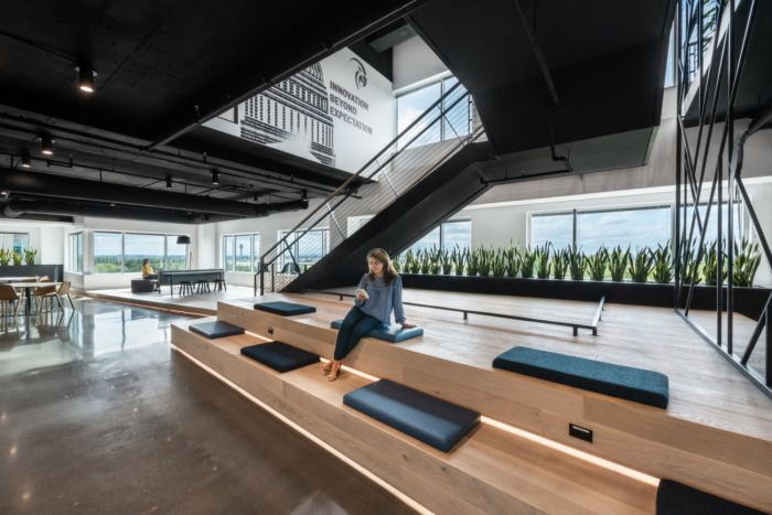 a woman sitting on top of a wooden bench in a room with lots of windows