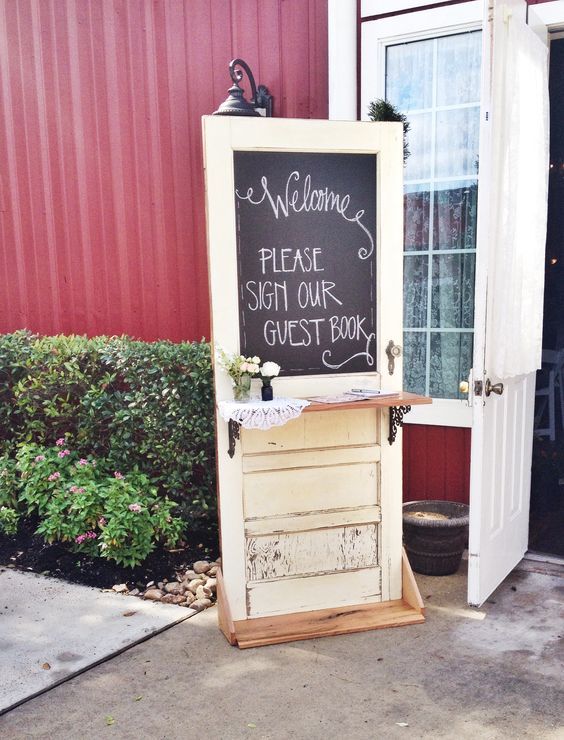 a chalkboard sign sitting in front of a red building with a welcome sign on it