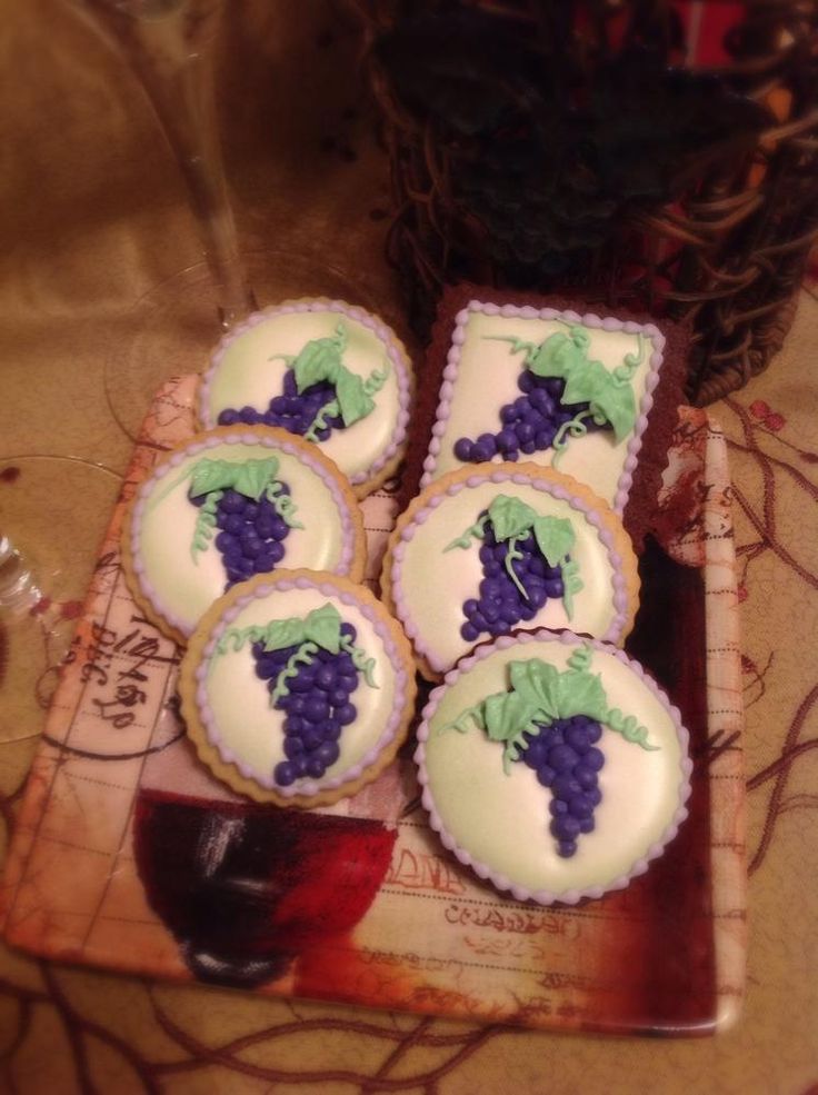 several decorated cookies sitting on top of a cutting board next to a glass of wine