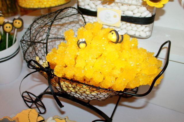 yellow candies are in a wire basket on a table with other candy and decorations