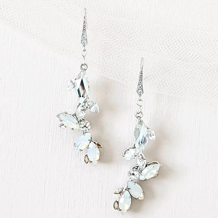 two pairs of earrings with crystal stones hanging from the ear wires on a white background