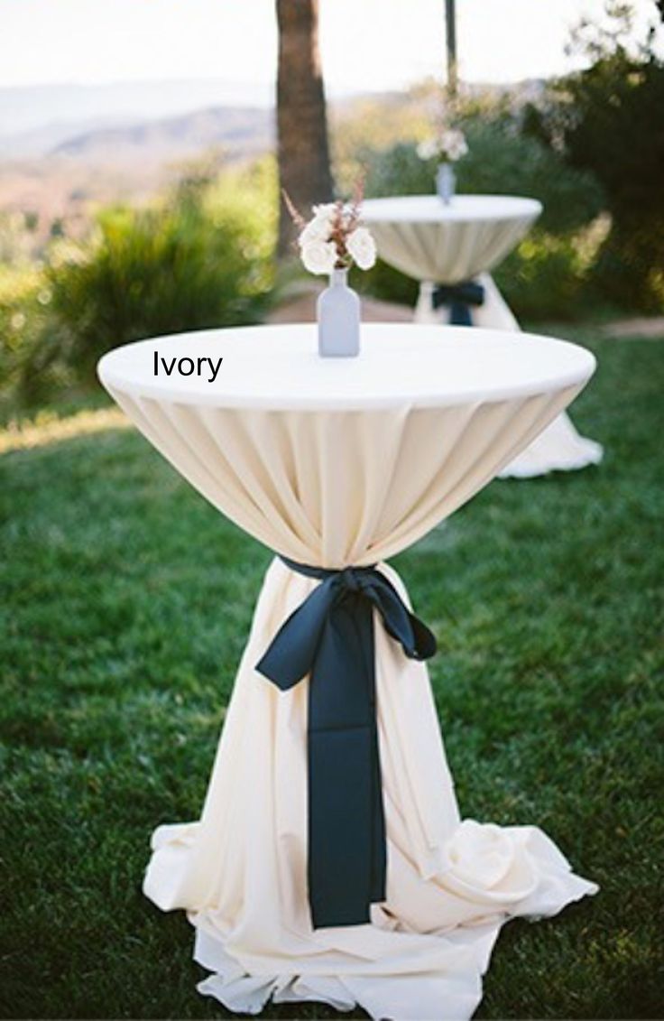 two white tables with blue sashes and flowers on them are sitting in the grass