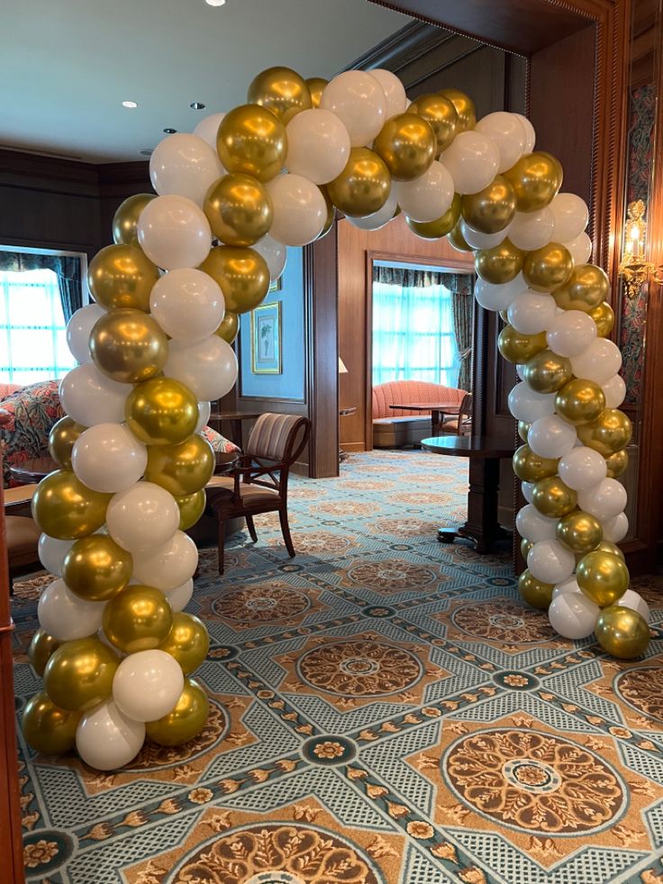 an arch made out of white and gold balloons