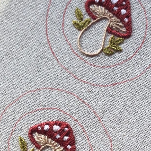 two pieces of fabric with embroidered designs on them, one is red and the other has green leaves