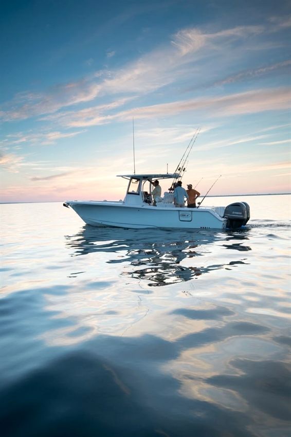 two people on a small boat in the water at sunset or dawn with one person fishing