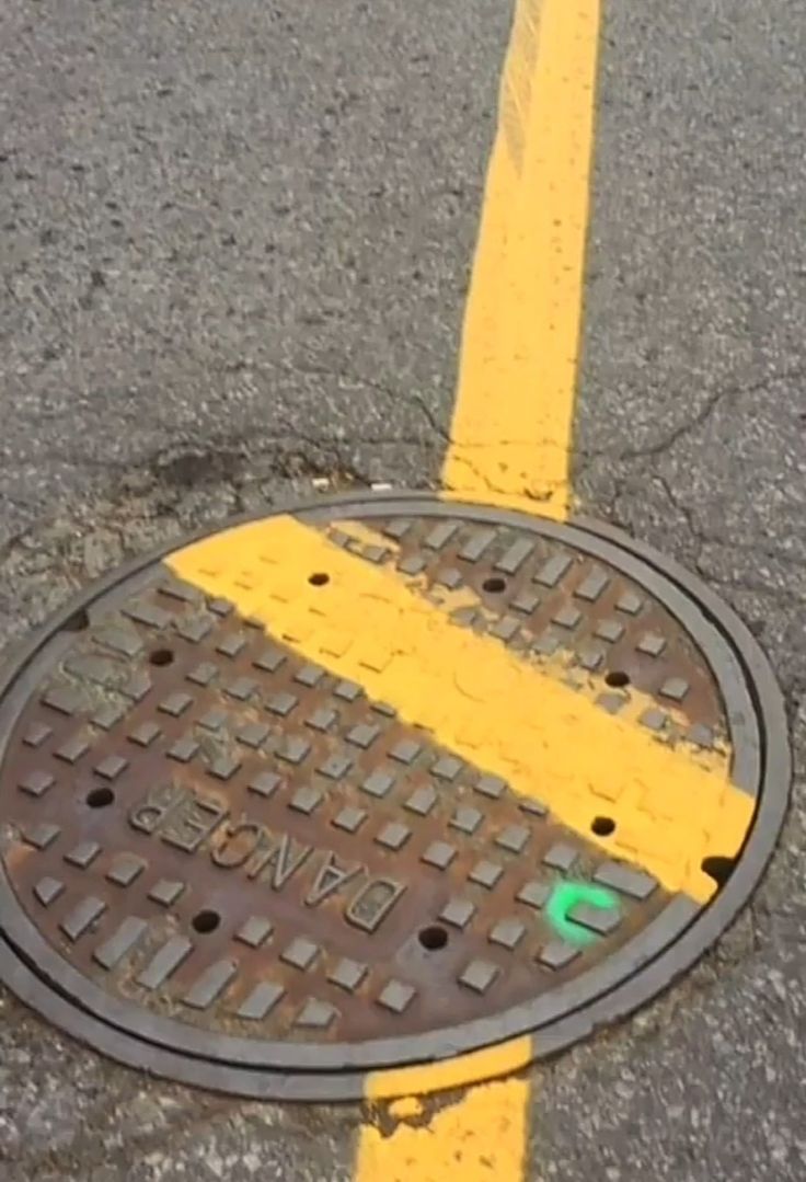 a manhole cover with yellow lines on the ground