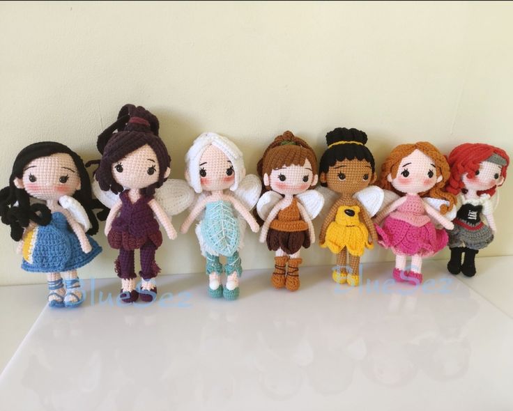 a group of knitted dolls standing next to each other on a table with white background