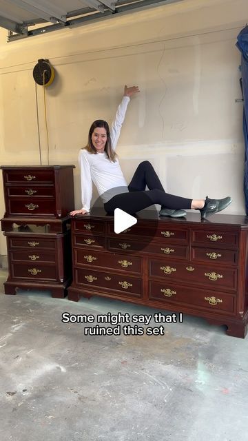 a woman sitting on top of a wooden dresser