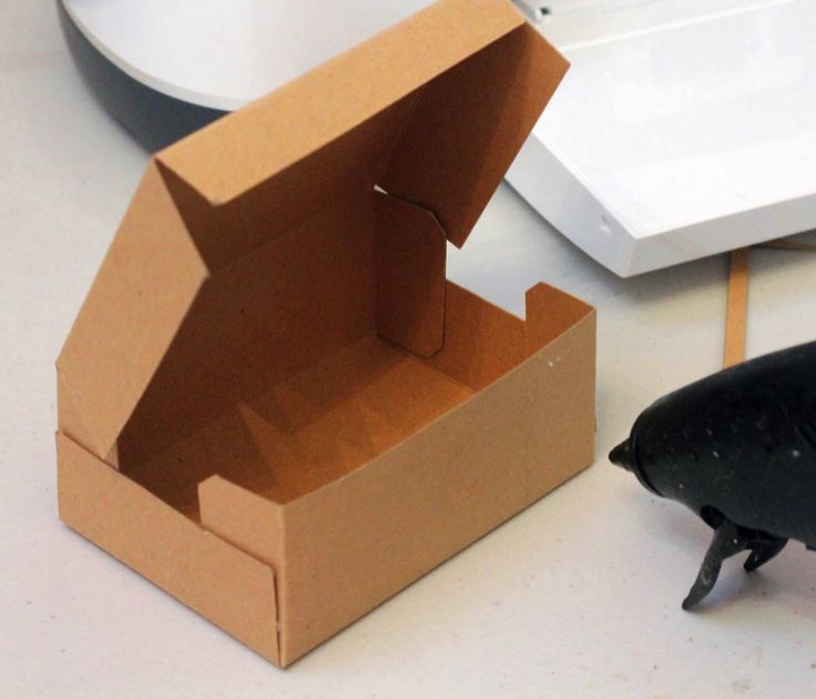 an open cardboard box sitting on top of a table next to a black plastic bird