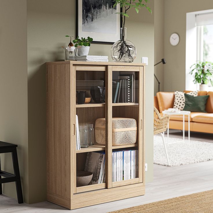 a living room filled with furniture and a plant on top of a book shelf in front of a window