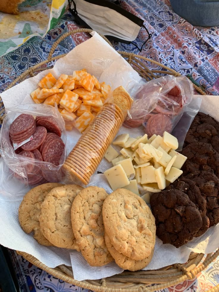 a basket filled with cookies, crackers and cheeses on top of a table