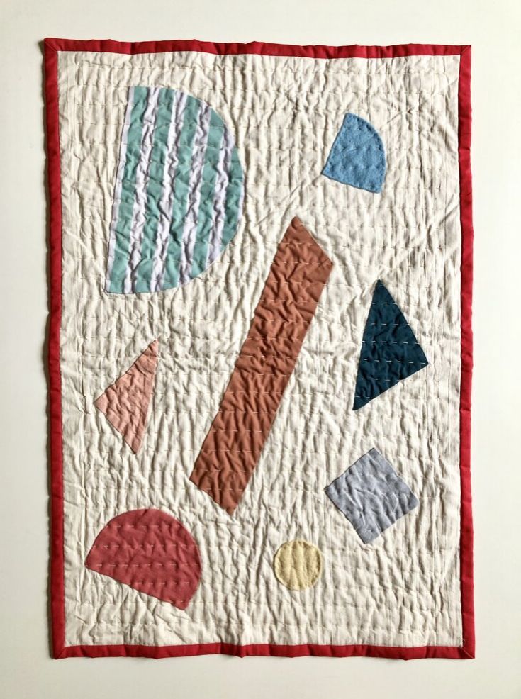 a quilted wall hanging with various shapes on it