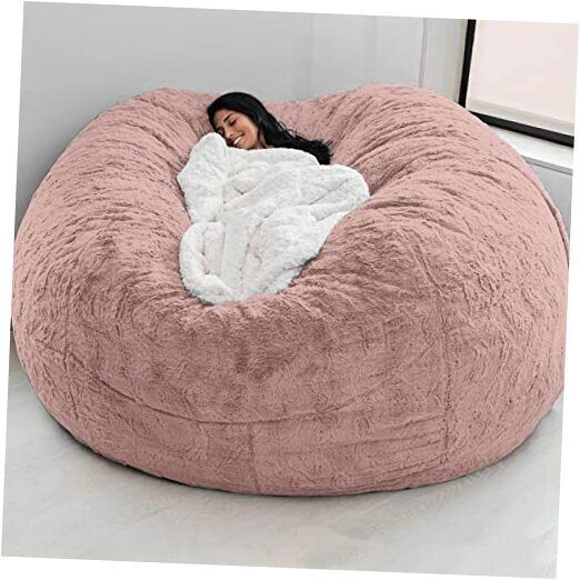 a woman laying in a large pink bean bag chair with a white blanket on it