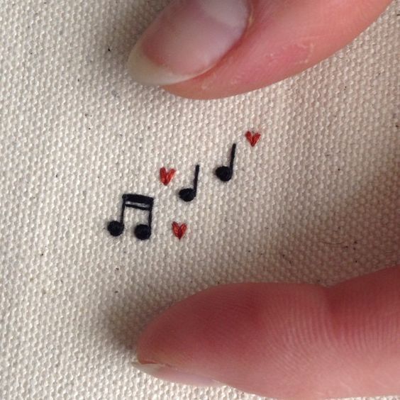 someone is stitching music notes and hearts on their fingers