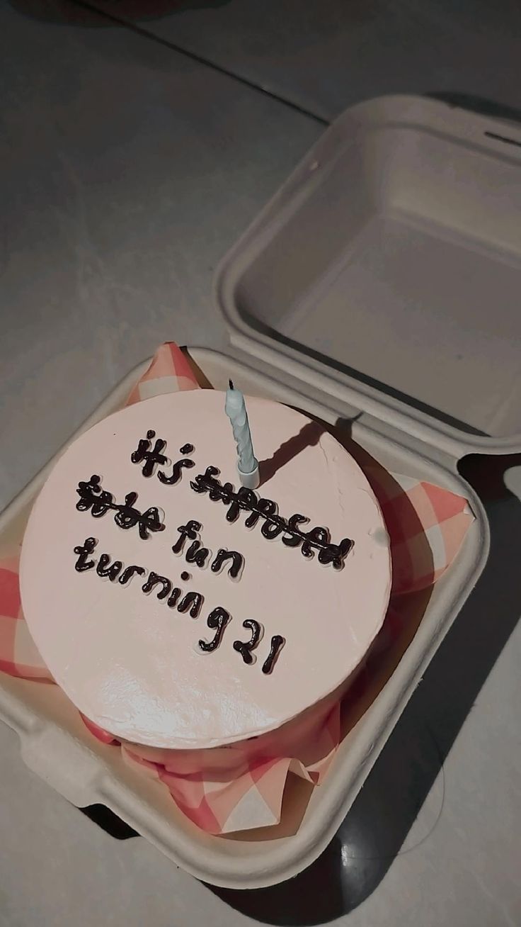 a birthday cake sitting in a container on the floor next to a fork and knife