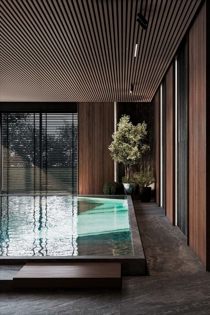 an indoor swimming pool in the middle of a room with wooden walls and flooring