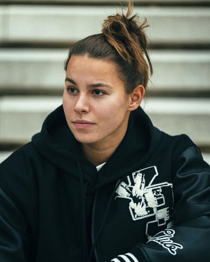 a young woman sitting down with her hair in a bun