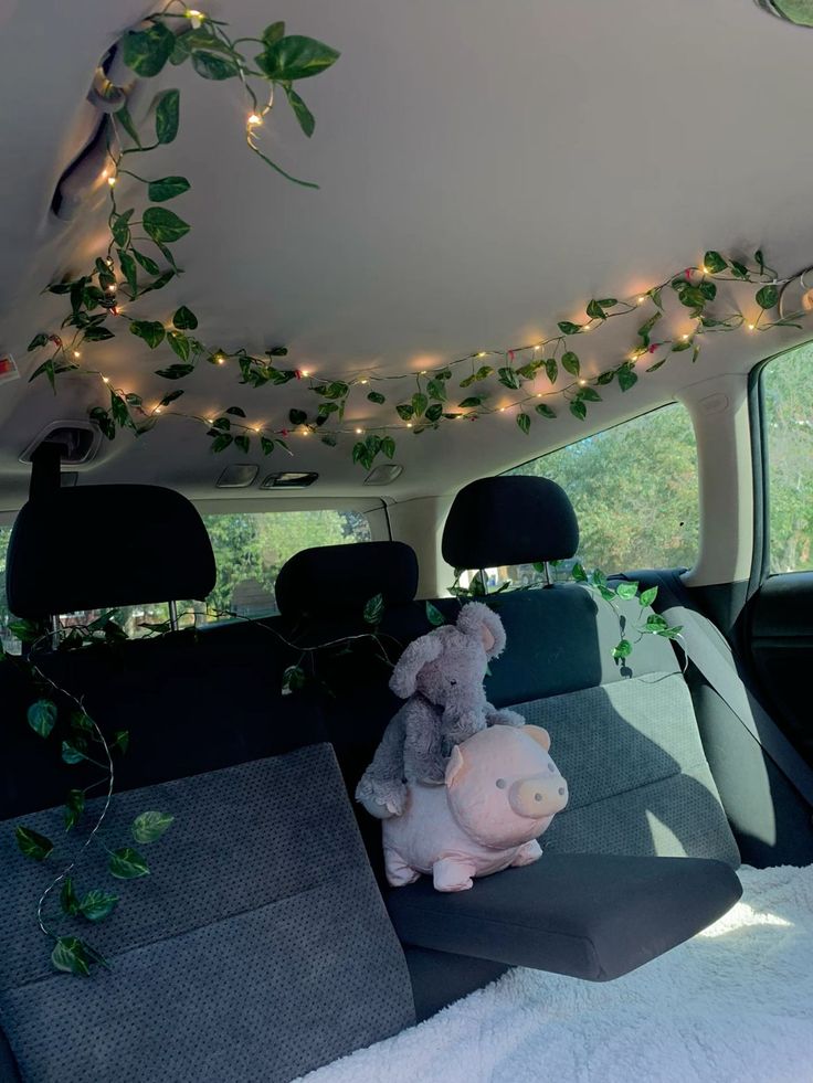 a stuffed animal sitting in the back seat of a car with lights strung above it