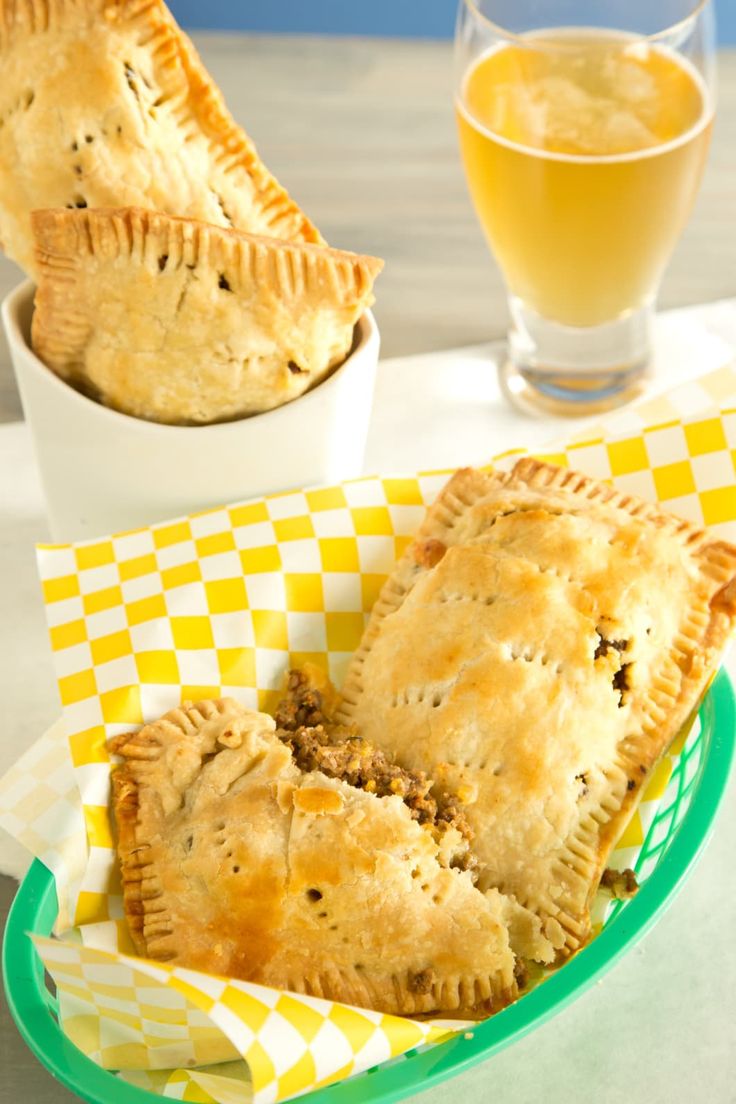 three pastries sitting in a basket on a table next to a glass of orange juice