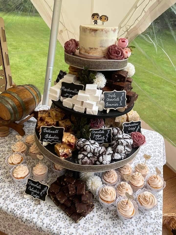 a tiered cake and cupcake display on a table