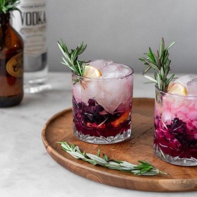 two glasses filled with drinks sitting on top of a wooden tray