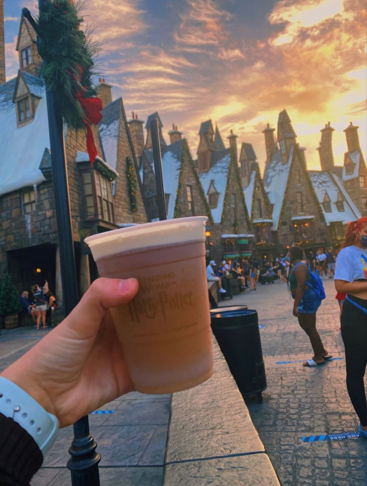 a person holding up a cup in front of a building