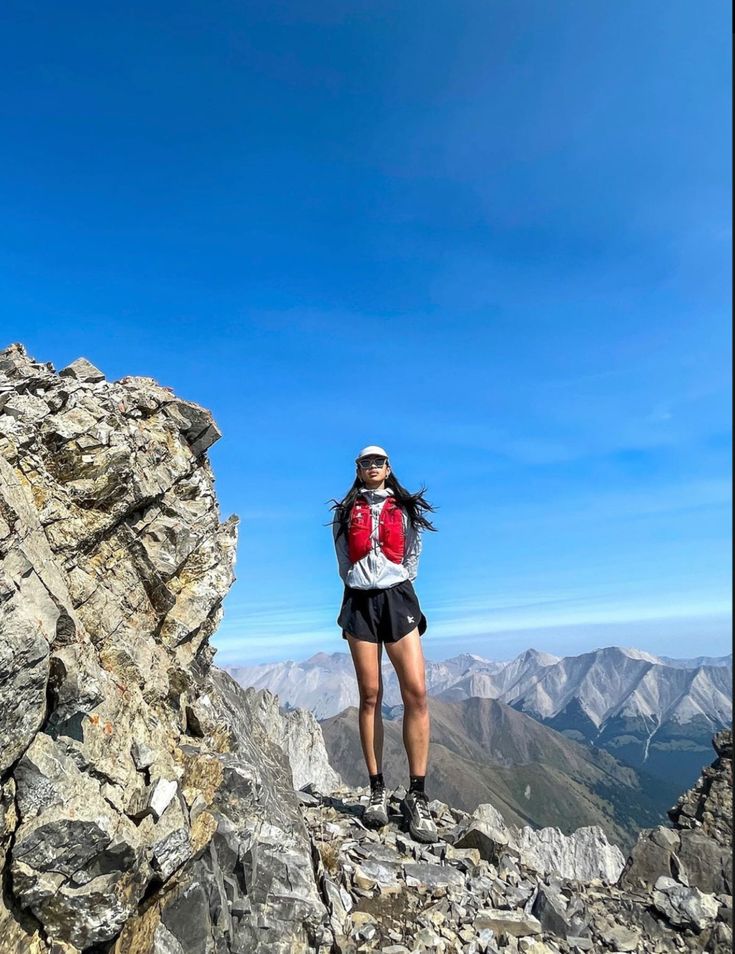 a woman standing on top of a rocky mountain