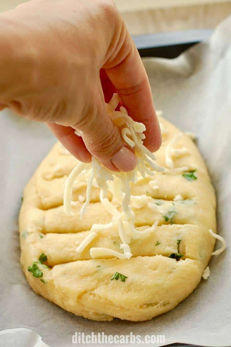 a person is sprinkling cheese on top of a pizza doughnut that's sitting on a baking sheet