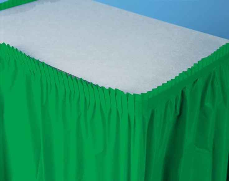 a green bed skirt with white sheets on it and blue wall in the back ground