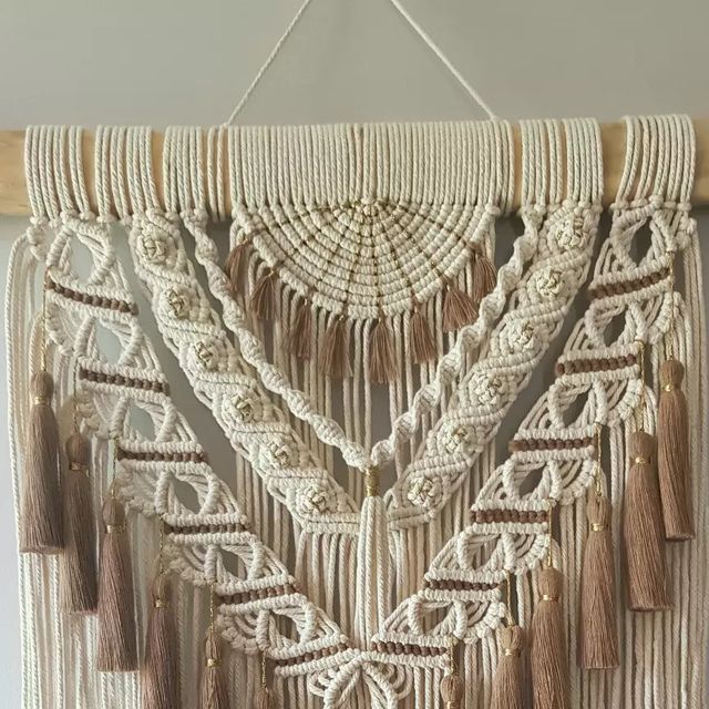 a macrame wall hanging with tassels and beads