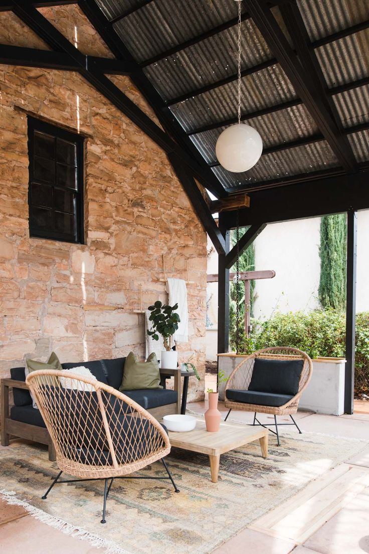 a living room filled with furniture next to a stone wall covered in plants and greenery