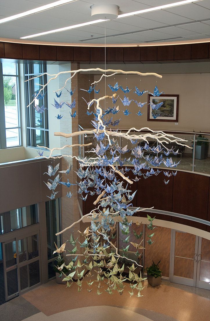 a glass sculpture in the middle of a lobby with blue and white butterflies hanging from it's ceiling