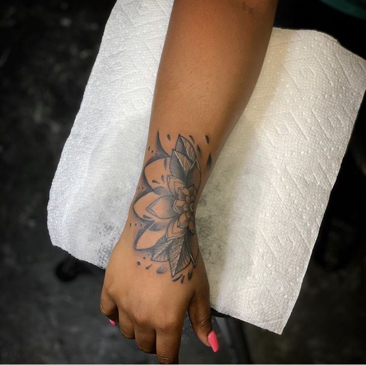 a woman's arm with a flower tattoo on it and a towel over her shoulder