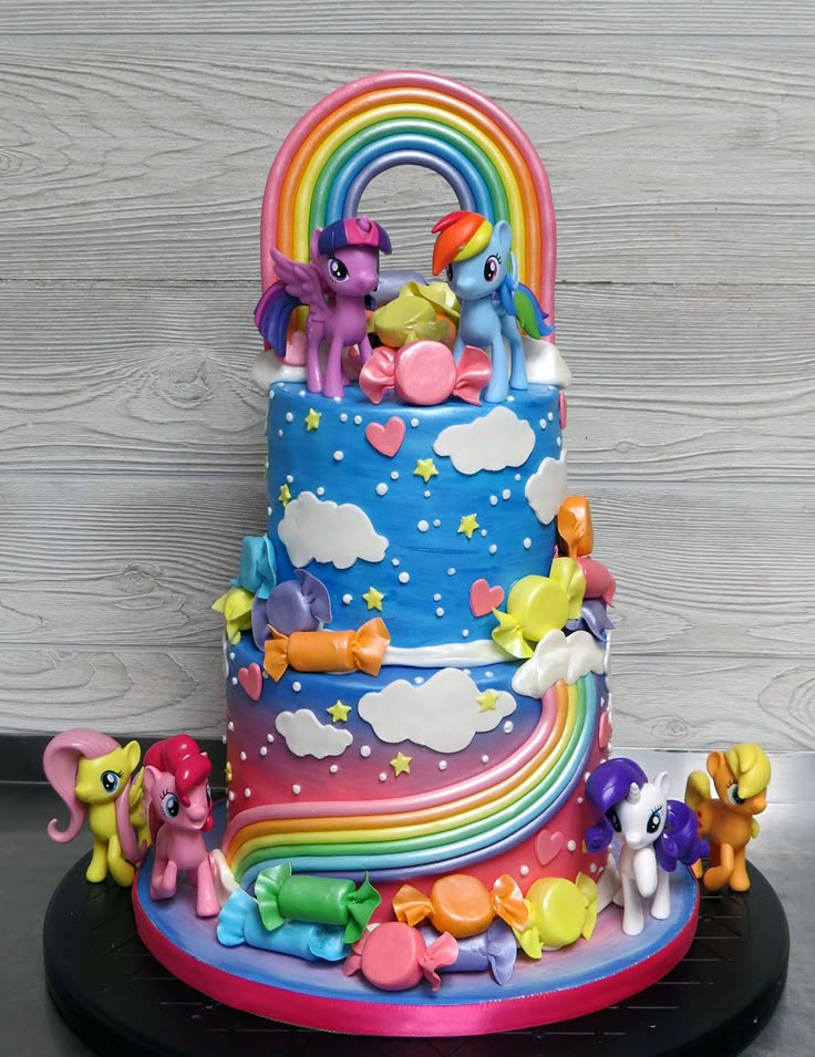 there is a rainbow cake with little pony figurines on it