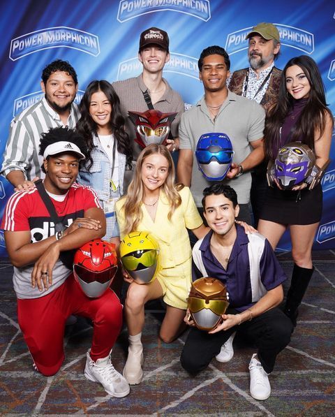 a group of young people posing for a photo with helmets on their heads and one holding a soccer ball