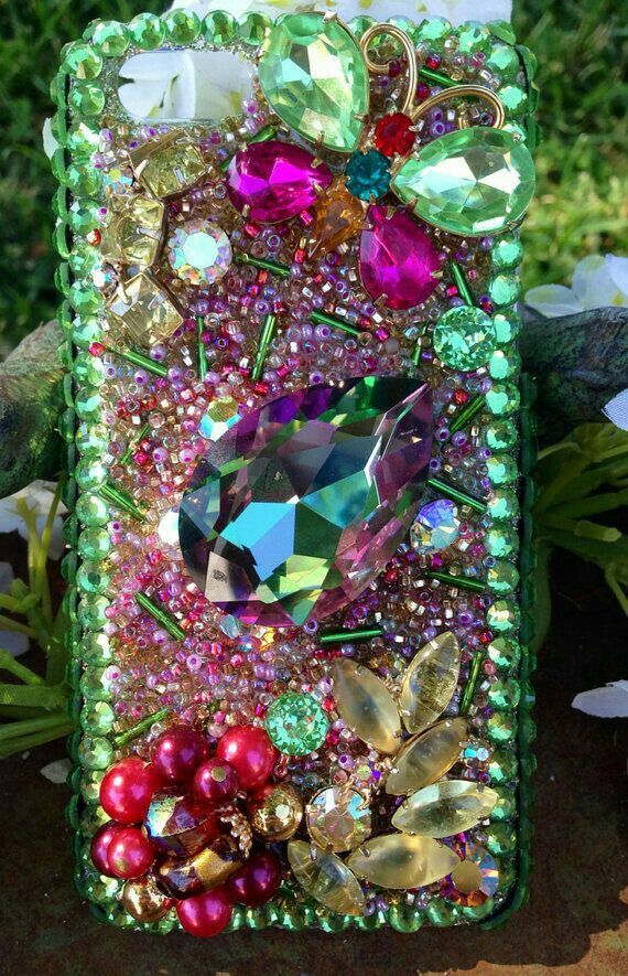 an iphone case is covered with jewels and pearls on the outside, as well as flowers