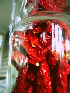 a glass jar filled with red peppers sitting on top of a table