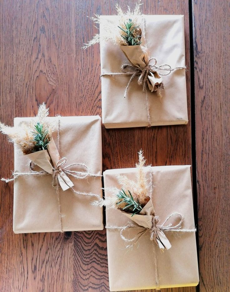 three wrapped presents tied with twine on top of a wooden table