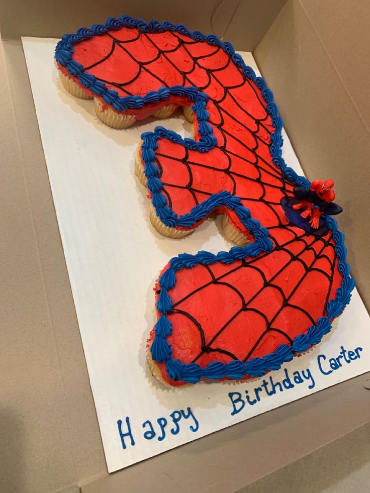 a birthday cake in the shape of a spiderman's face on top of a cardboard box