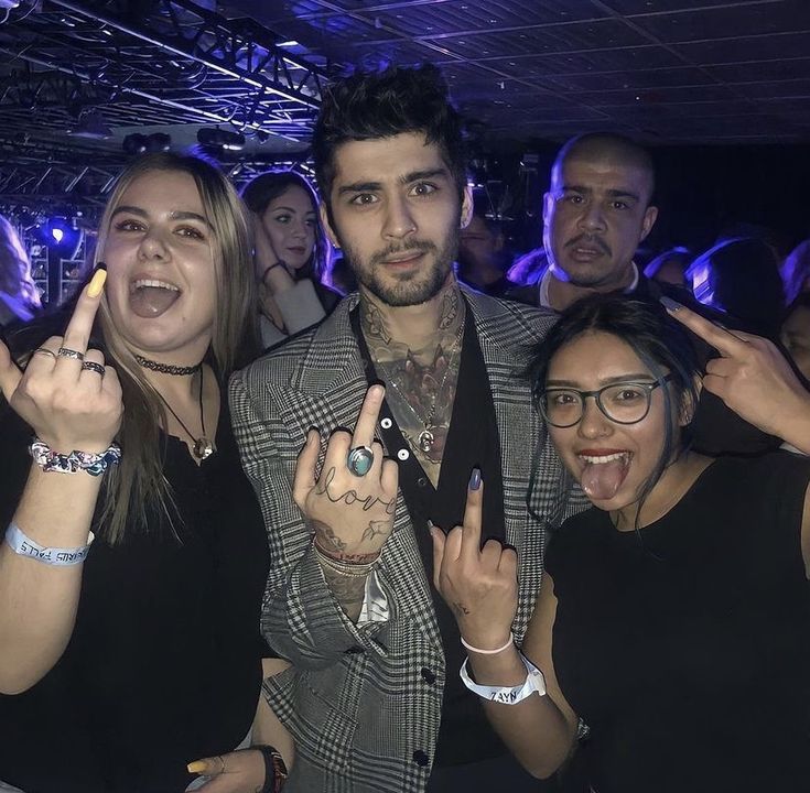 a group of people standing next to each other in front of a crowd with their fingers up