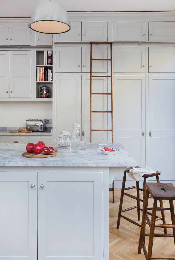 a kitchen with white cabinets and wooden stools next to an island in the middle