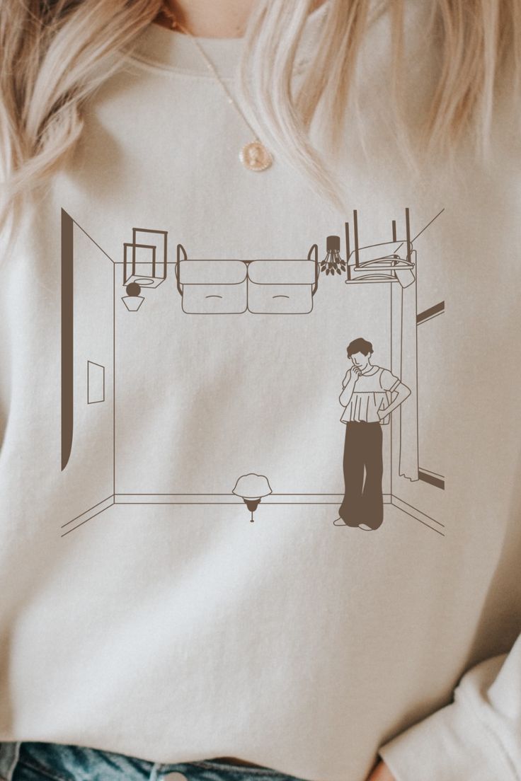 a woman wearing a white shirt with a drawing of a person standing in a room