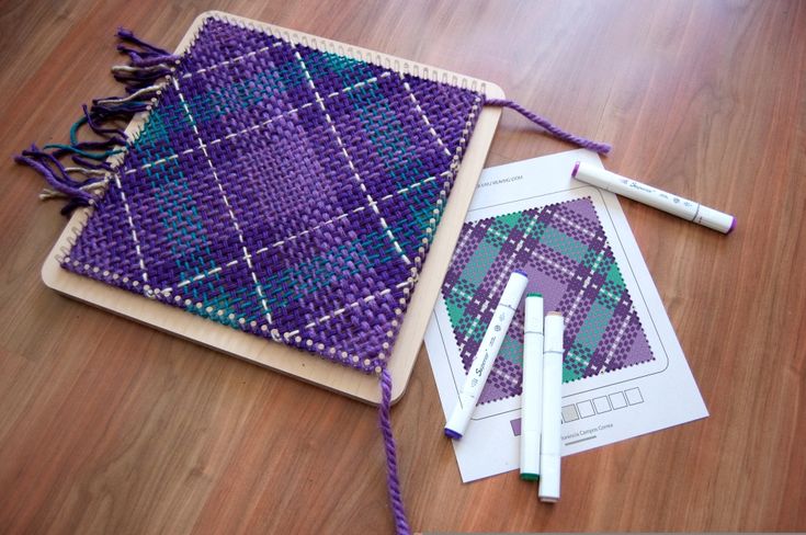 a purple and green piece of cloth next to some crochet needles on a wooden table