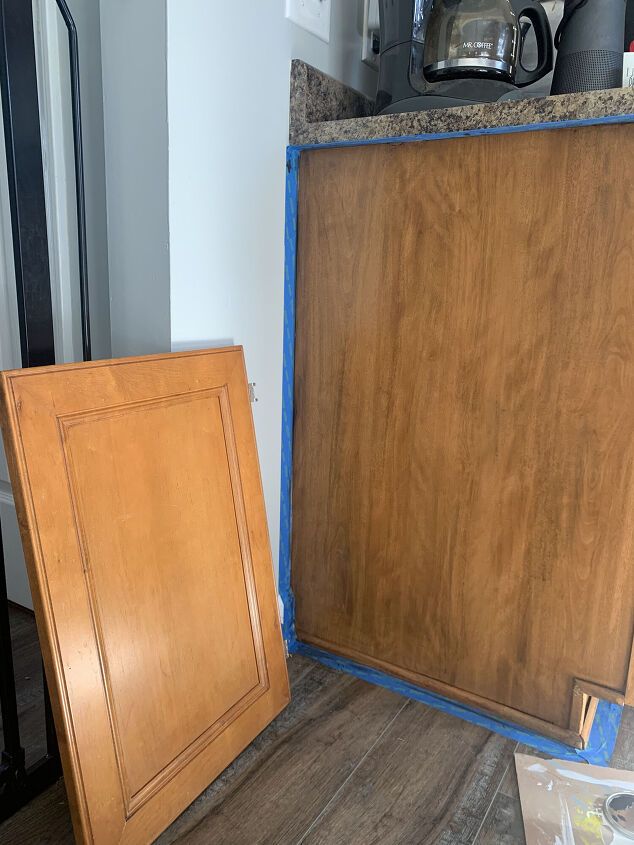 a wooden cabinet with blue tape around it and a tea kettle on the counter top